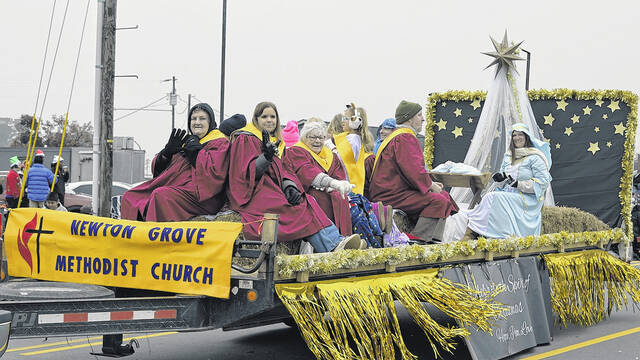 Members of the Newton Grove Methodist Church brave the cold, misty weather Saturday to display their float depicting the birth of Jesus, the true reason for celebration of the Christmas season. They, along with dozens of others, smiled and waved to a packed crowd of parade-goers who bundled up to enjoy the towns second kick-off to the holiday season following the Circle of Lights just over a week ago. See more photos Page 6A.