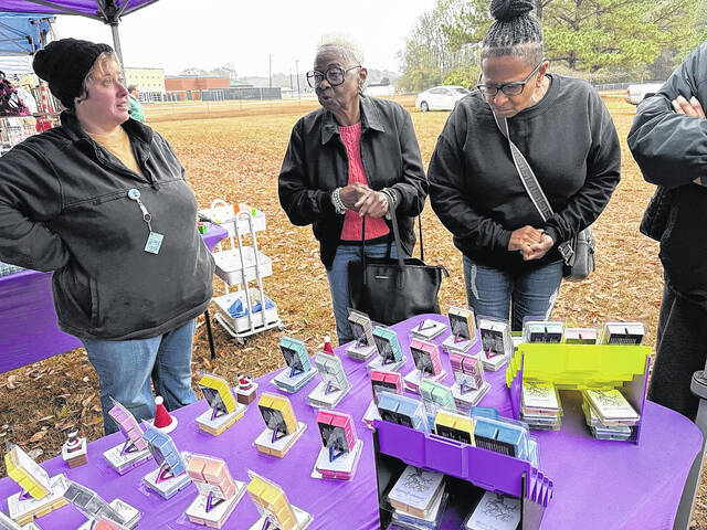 Twizted CreationZ owner Kayla Allen stands by as customers look at a set of scented wax melts, one of the many booths set up in Salemburg Saturday.