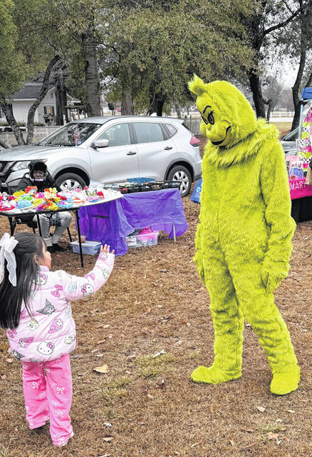 The Grinch greets a youngster Saturday at Salemburgs Small Town Christmas.