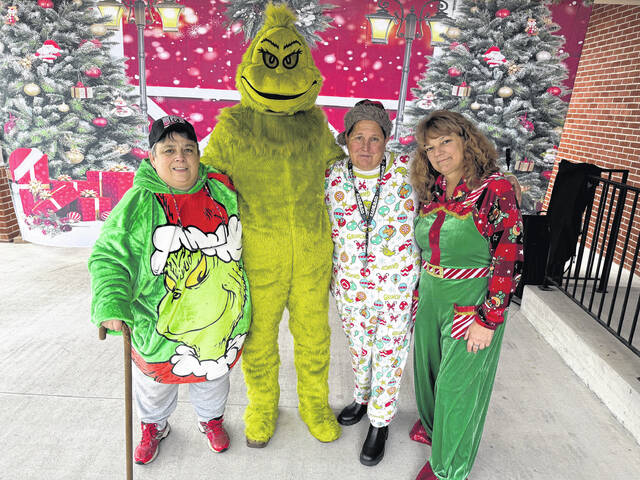 The Grinch stops long enough Saturday to have his photograph taken with, from left, Barbara Thornton, Jane Hodges and Diana Herwy during Small Town Christmas.
