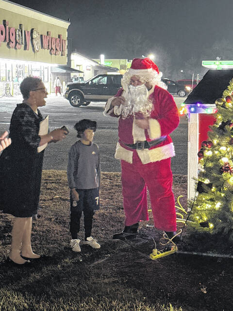 Garland Mayor Pro Tem Carolyn Melvin laughsas Santa and Miguel Deleon from Ingold light up the tree Saturday evening.