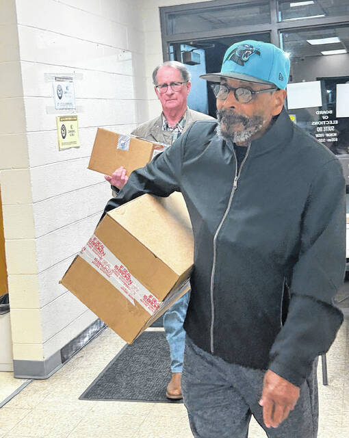 Board of Elections members Franklin Brown, foreground, and Dwight Williams bring in boxes of sealed ballots Tuesday night.
