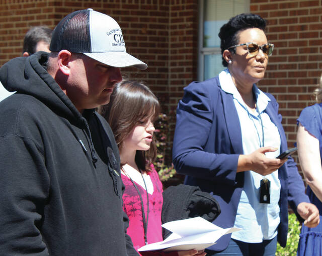 Kaylie Robbins, second from left, reads a statement during Fridays pinwheel planting ceremony. She is flanked by Sheriffs Office Detective Andrew Worley and Angela Freeman, CPS supervisor.