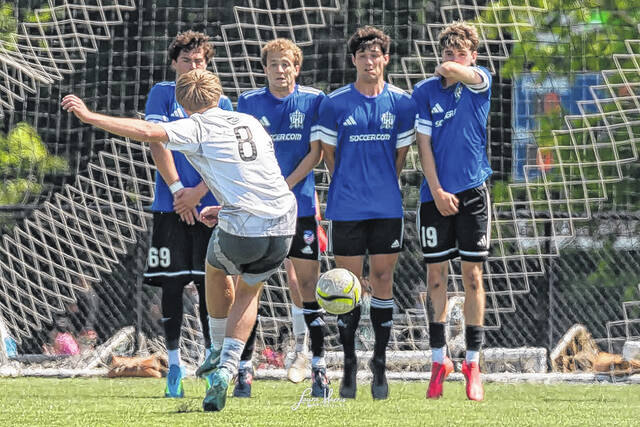 Defenders of the United jump in unison to block an opposing penalty kick.