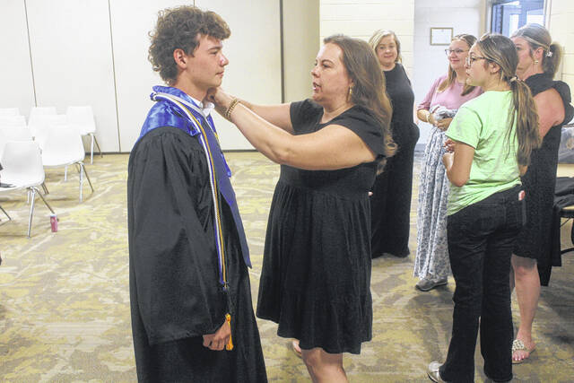 Sampson Early College teacher Ashley Stanley fixes Stephen Melvins collar prior to the ceremony Thursday.
