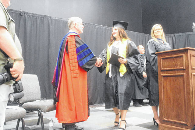 Jenny Hobbs shakes the hand of Dr. Robert Hunter, pastor of Mintz Baptist Church, as she walks the stage with her diploma Thursday.