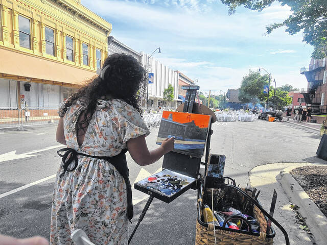 Artist and live wedding painter Skyler Hope Cason works diligently on a landscape painting of the Sampson County Courthouse and the real-time ambiance of Sundays Dinner on Main. (Sherry Matthews|Sampson Independent)