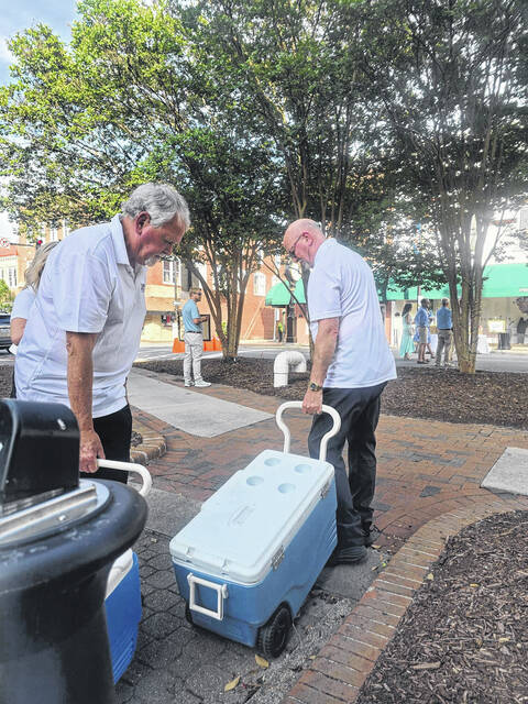 Bill Scott and Stan Roberts, Main Street volunteers, haul coolers filled with crisp, clean award-winning Clinton water toward downtowns Main Street, where they would be set up for diners to drink. (Sherry Matthews|Sampson Independent)
