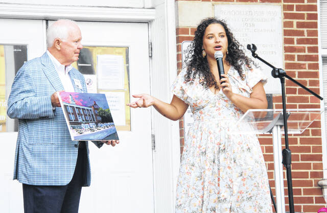 Artist Skylar Hope Cason, accompanied by Sampson Economic Development Director Ray Jordan, explains her thought process with a painting she did live at the event.
                                 A. Goodman | Sampson Independent