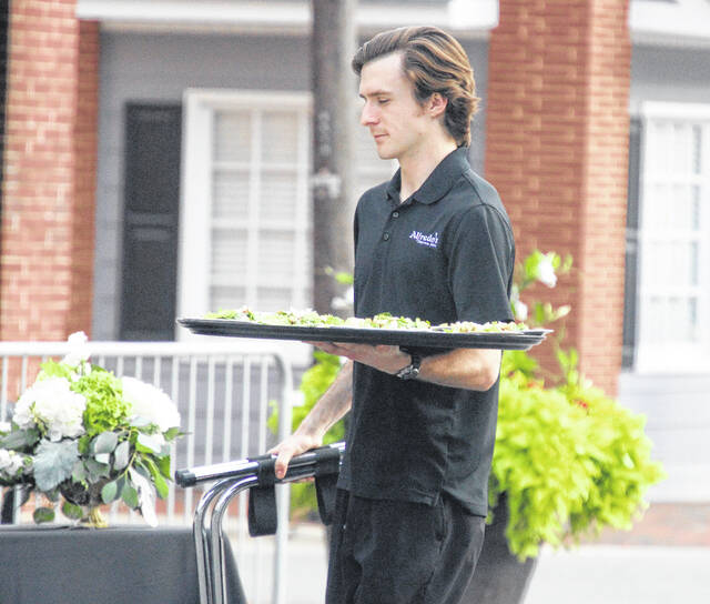 Server Harrison Williams of Alfredos moves effortlessly down a line of guests as the first course is served.
                                 A. Goodman | Sampson Independent