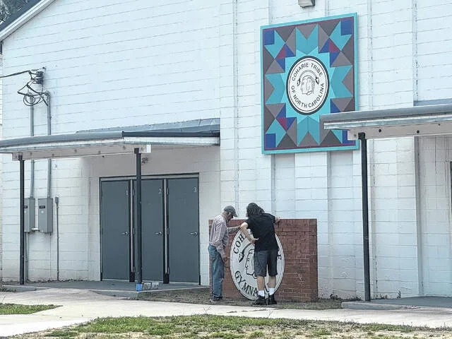 Joe Jones, local housing director, looks with Keith Carter at where the new Coharie logo will be placed.