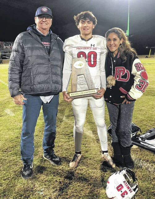 Jacob Baggett, center, along with his dad Bill and his mom Patty, showing off the state championship trophy.
