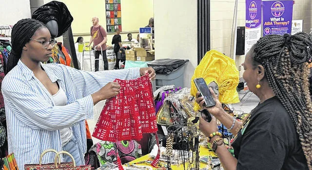 Chiamaka Anyagaligbo shows Sylvia Jacobs a red skirt for sale at the vendor table for Donum African Store at the Sampson Juneteenth celebration Friday.
                                 Trevon McGlone | Sampson Independent