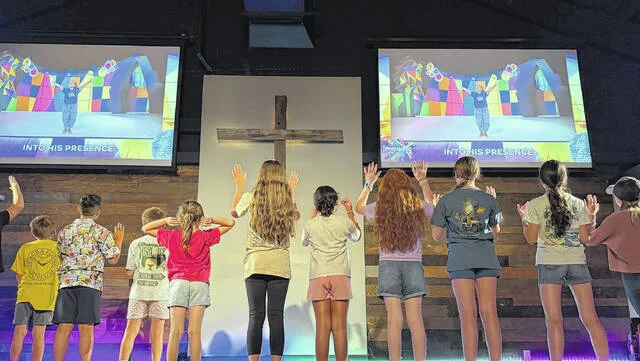 Youngsters at The Vine on U.S. 701 in Clinton emulate activites shown on the screen during worship time through song and interpretation as part of their Illumination Station activities during their VBS. (Courtesy photo)