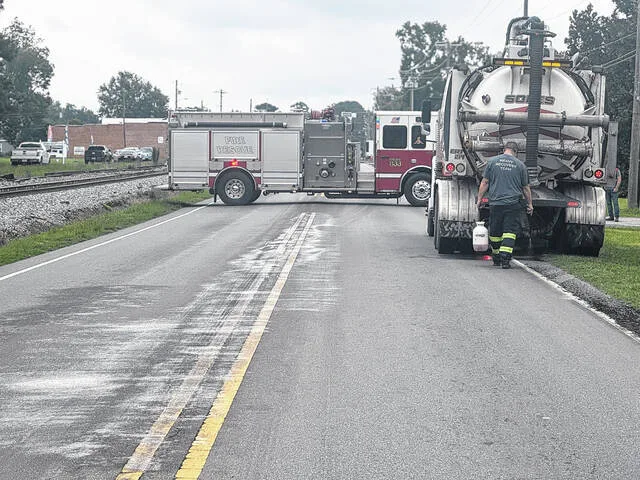 A Heavy Recovery Team member cleans up the byproduct spill along Turkey Highway Monday morning. The tanker truck driver, Kenneth Higginbotham, is charged with failure to secure load, littering 10-500 lbs, and failure to stop in event of certain spills from vehicles.
                                 Dylan Atwood | Sampson Independent