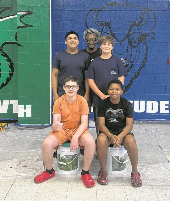 Roseboro-Salmeburg Middle School art teacher Jemeikka Steele, back, poses with some of the students who help her paint the latest mural in the schools cafeteria. Pictured with Steele are, front, from left: Waylon Sealy and Kaiden Logan; and second row: Jayden Caceres and Grayson Pope,