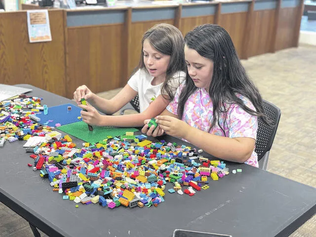 Taylor and Ansleigh pick through their bricks as Ansleigh fashions an umbrella at the Holliday Librarys Lego Lab.
                                 Dylan Atwood | Sampson Independent