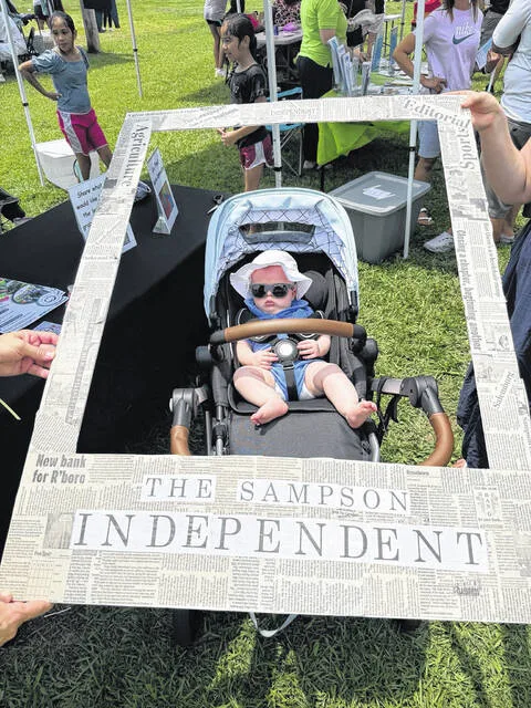Four-month-old Darren Samuel King, son of Gabrielle and Anthony King of Roseboro, is dressed in shades and a hat to protect him from the sun as he makes his newspaper debut, framed in The Sampson Independent. Carla Sutton, coordinator for the Lakewood Community Literacy Partnership, provided the newspaper frame which she and SI Publisher Sherry Matthews used all day Saturday at the partnership booth as a means of spreading word about the initiative and offering children and their families an opportunity to mug for the camera and appear in the local newspaper. See more photos 9A-10A today and editorial about the day 6A.