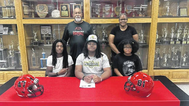 Union High Schools Caleb Robinson is surrounded by his teammate, Tobias Cromartie, coach Mark Oates, and his mother and sister, Cammie and Imani as he prepares to sign his letter of intent Wednesday, Aug. 5.
Trevon McGlone | Sampson Independent