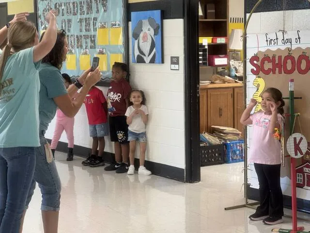 Miss Judy Coombs and Miss Ellen Wiley, pre-K teacher assistant and kindergarten teacher, respectively, at Kerr Elementary encourage kindergartener Marielly to pose for her first day of school photo Monday.
Dylan Atwood | Sampson Independent