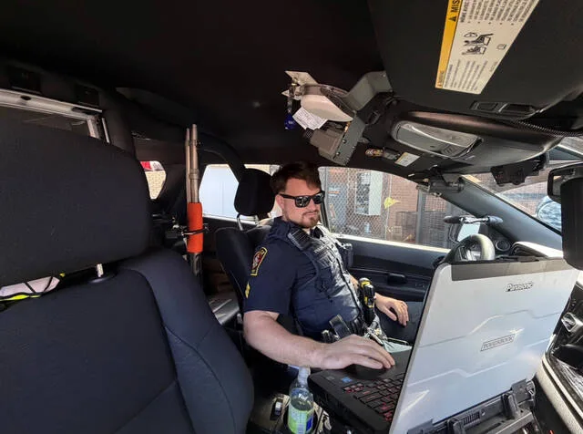 Sgt. Mark Horne sits in his police car with a less-lethal shotgun in the backseat that is equipped with drag-stabilized bean bag rounds.
Courtesy photo | Clinton Police Department