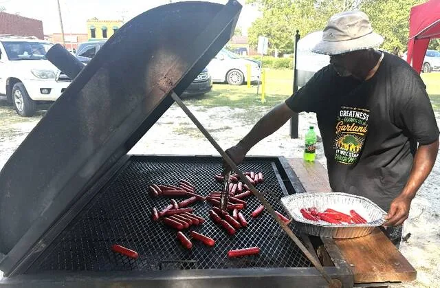 Garland Commissioner Sean Melvin mans the grill where hotdogs were cooking Saturday.
                                 Trevon McGlone | Sampson Independent