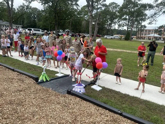 Linda Warren helps Salemburg kids cut the ribbon to the playground.