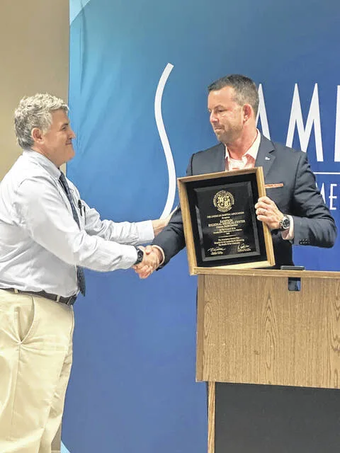 Sampson Regional CEO Dr. Shaw Howerton receives a token of acknowledgement from Matthew Wright of the American Hospital Association.