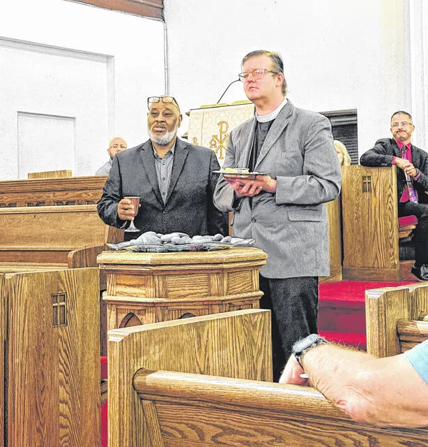 Pastor William Sankey Jr. of Reborn Ministries, and the Rev. Gary Fetter of St. Pauls Episcopal Church offer communion to all in attendance as part of remembering and lamenting 9/11. In front of the ministry leaders is the baptismal font, which is filled with stones. Each person had the opportunity to place a stone in the water as a physical representation of heaviness and grief related to both the tragedy of 9/11, and the personal pain anyone may be carrying.
                                 Photos by Claire Fox | Sampson Independent