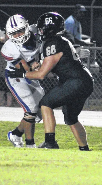 Clinton senior center Brady Warren makes a block on the Wolfpack defender during Friday nights game.